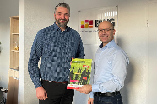 Zwei Geschäftsführer der Blankenburger Wohnungsgesellschaft (BWG) präsentieren die neue Wohnungsbroschüre „Mein Zuhause“ im Unternehmenssitz in Blankenburg (Harz)          ChatGPT fragen