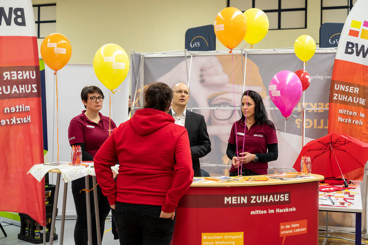 Messestand der BWG bei einer Karrieremesse in Halberstadt mit bunten Luftballons, Informationsmaterial und Mitarbeitenden im Einsatz für das Wohnungsunternehmen