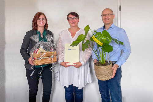 Gratulation zur bestandenen IHK-Prüfung bei der BWG Blankenburg: Drei Mitarbeitende mit Urkunde, Geschenkekorb und Pflanze