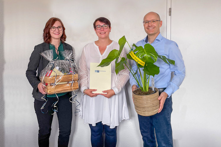 Gratulation zur bestandenen IHK-Prüfung bei der BWG Blankenburg: Drei Mitarbeitende mit Urkunde, Geschenkekorb und Pflanze