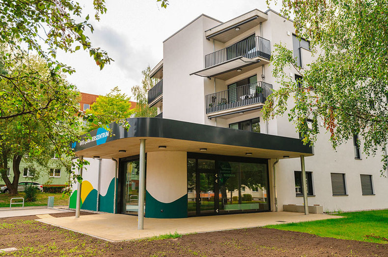 Foto des Quartierszentrums Regenstein in Blankenburg mit moderner weißer Fassade, Balkonen und überdachtem Eingangsbereich in grün-weißer Gestaltung.