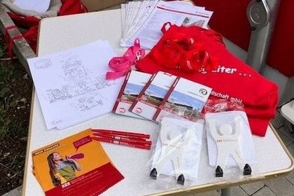 Werbematerial der Wohnungsbaugesellschaft auf einem Infotisch: Broschüren, Baupläne, Kugelschreiber, Schlüsselbänder, Give-aways und ein rotes T-Shirt mit Slogan – Einsatz bei Veranstaltung zur Mieterinformation in Halberstadt