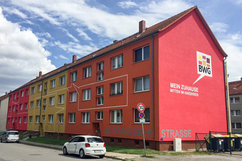 Fertig sanierte Wohnhäuser in der Börnecker Straße 36–38 im Quartier Regenstein. Die Fassade erstrahlt in kräftigen Gelb-, Orange- und Rottönen. Auf der Stirnseite des Gebäudes sind das Logo der BWG sowie der Slogan „Mein Zuhause mitten im Regenstein“ deutlich sichtbar.