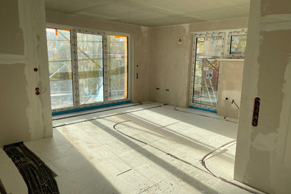 Innenaufnahme eines Neubaus der BWG Blankenburg mit vorbereiteter Fußbodenheizung und großen Fensterflächen im Rohbauzustand