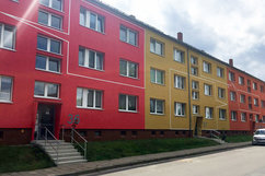 Frontalansicht der frisch sanierten Wohnhäuser Börnecker Straße 36–38 im Quartier Regenstein. Die Fassade ist farbenfroh gestaltet in Rot- und Gelbtönen, mit weiß abgesetzten Linien.