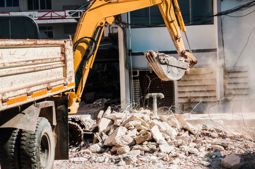 Abrissarbeiten mit Bagger und Lkw – Baumaschinen räumen Bauschutt vor Wohngebäude