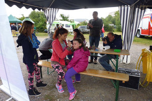 Kinderschminken unter einem Pavillon beim Nachbarschaftsfest.
