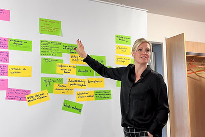Wohnungswirtschaft Blankenburg: Mitarbeiterin präsentiert Ergebnisse eines Workshops zur Quartiersentwicklung an einer Moderationstafel mit farbigen Karten