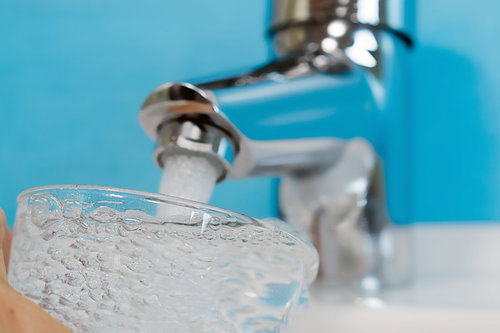 Trinkwasser wird aus einem Wasserhahn in ein Glas gefüllt zur Überprüfung der Qualität des Wassers.