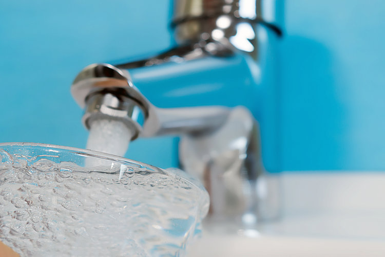 Trinkwasser wird aus einem Wasserhahn in ein Glas gefüllt zur Überprüfung der Qualität des Wassers.