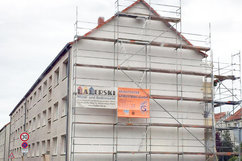 Giebelseite der Wohnhäuser Börnecker Straße 36–38 im Quartier Regenstein während der Fassadensanierung. Das Gebäude ist vollständig eingerüstet, ein Bauunternehmen-Banner und ein Hinweis zur energetischen Sanierung sind am Gerüst angebracht.