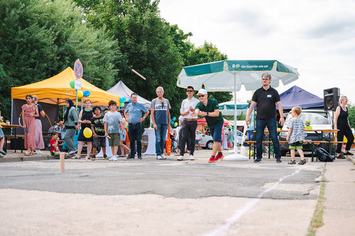 Menschen verschiedener Generationen spielen Wurfspiel beim Stadtteilfest im Quartier Regenstein – bunte Zelte, fröhliche Stimmung und Gemeinschaft im Fokus.