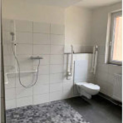 Barrierefreies Badezimmer in einer sanierten Wohnung der BWG in Blankenburg mit bodengleicher Dusche, Haltegriffen und erhöhtem WC – senioren- und rollstuhlgerecht